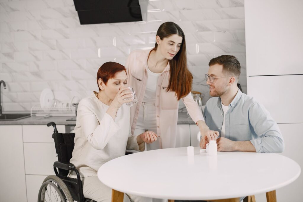 Family and caregiver talking with a senior woman in a bright kitchen
