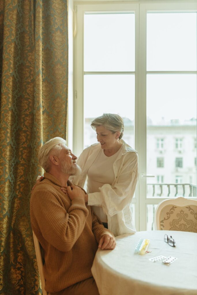 An older couple together at a table by a window at home