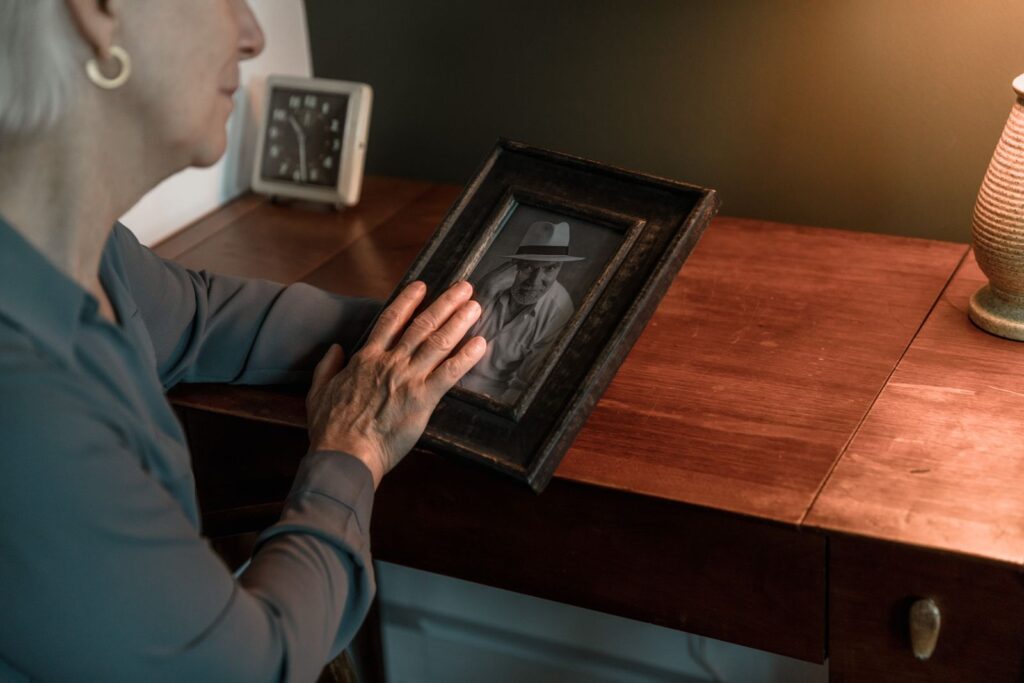 An older woman holding a framed photograph at home